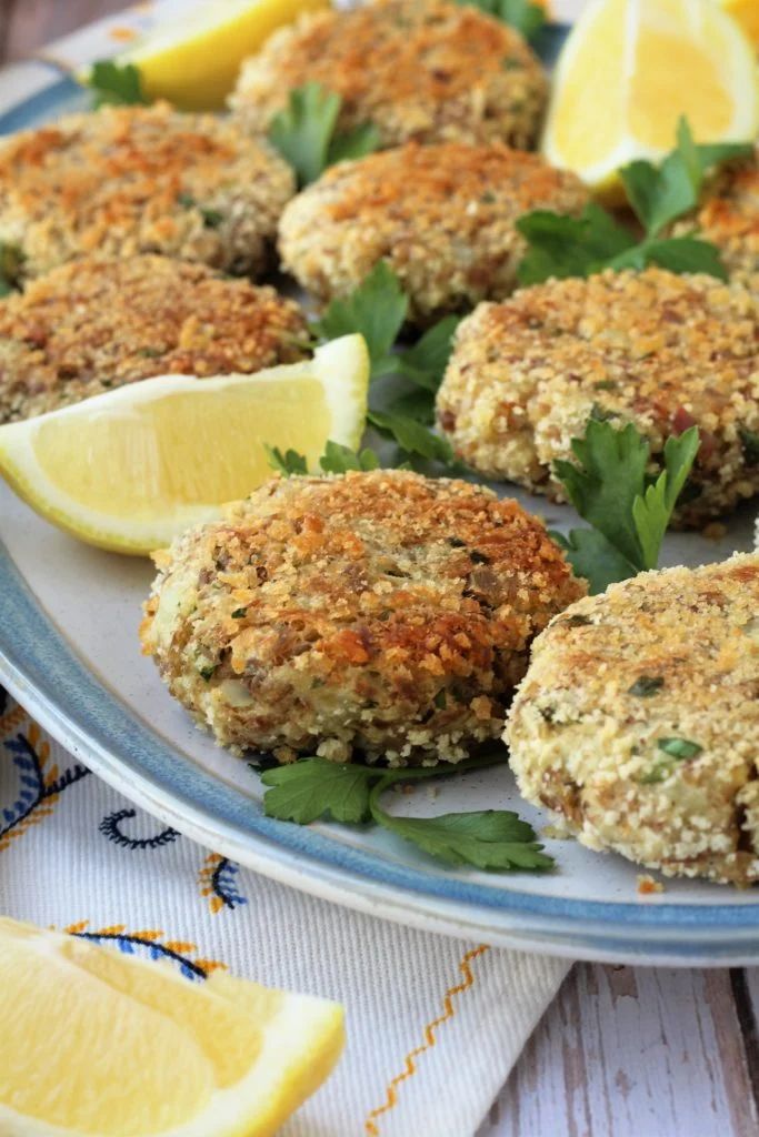 crab cakes on a plate with lemons and parsley