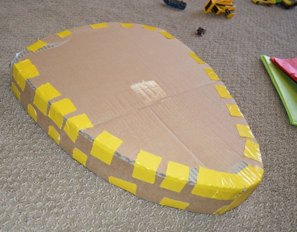 a cardboard cut out of a yellow and brown object on the floor next to other toys