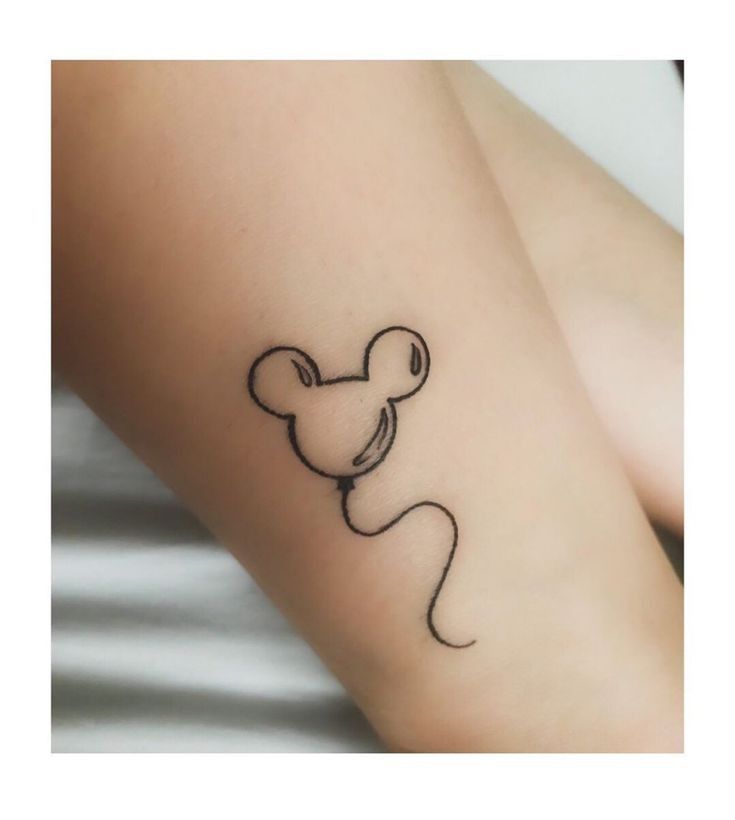 a small mickey mouse tattoo on the left arm and leg, with a black outline