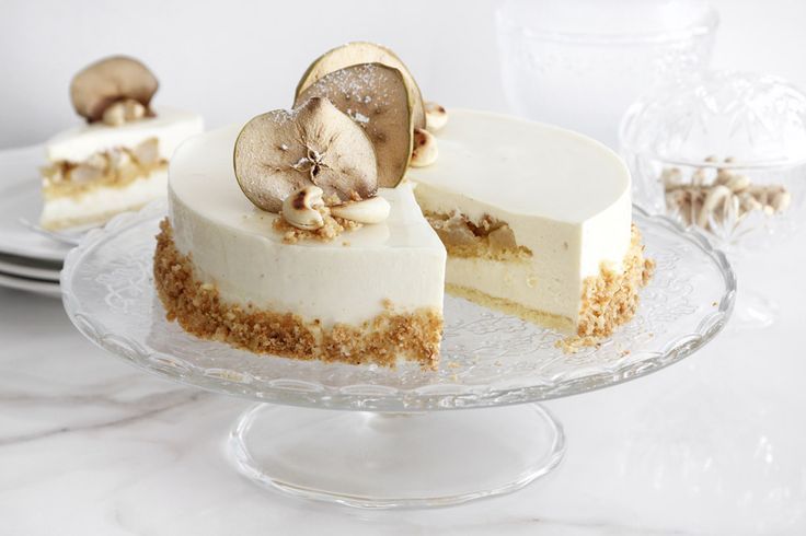 two slices of cheesecake on a glass cake plate with silverware in the background