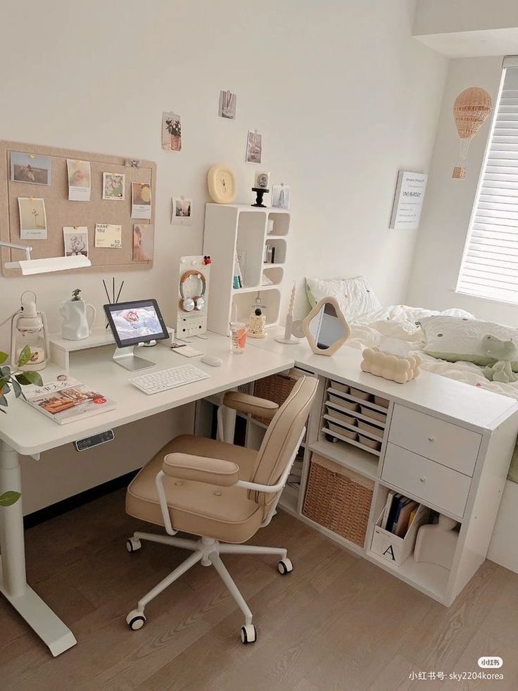 a white desk topped with a laptop computer next to a chair and bookshelf