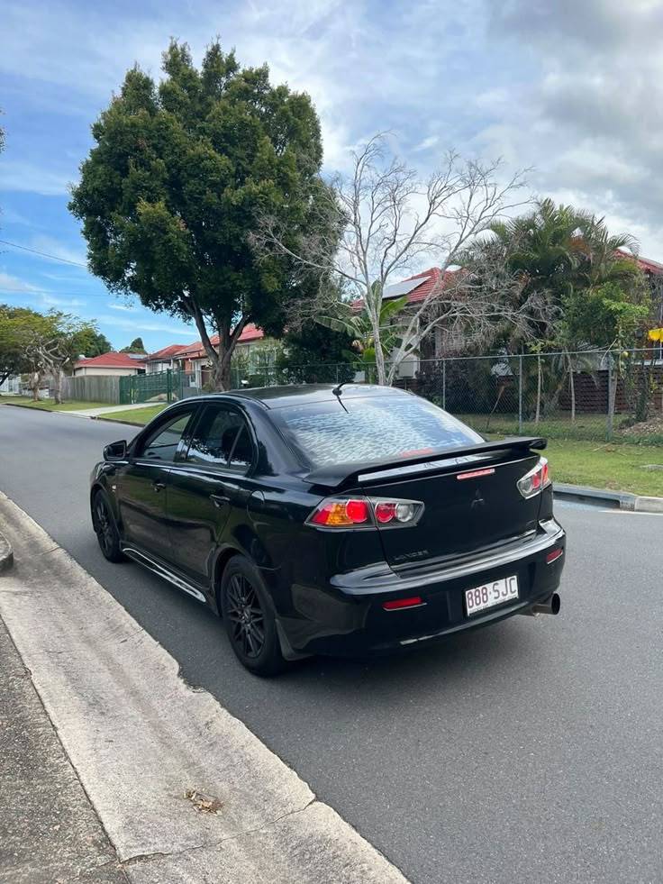 a black car is parked on the side of the road