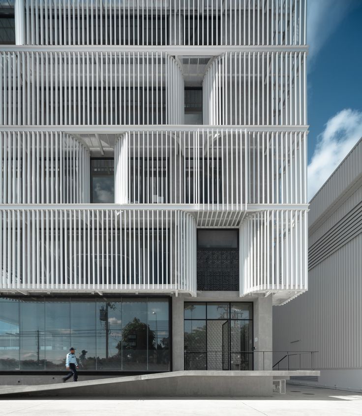 a person walking in front of a building that has white slats on the side