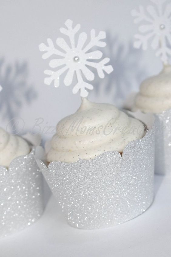 three cupcakes with white frosting and snowflakes