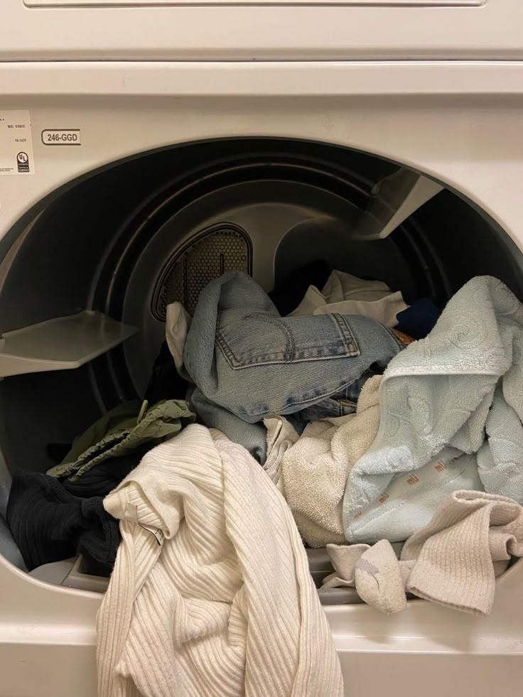 an open washing machine with clothes in it