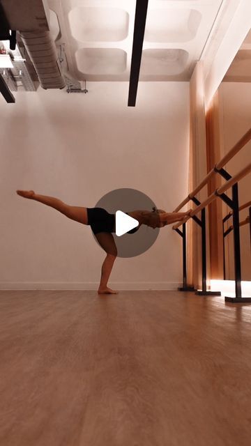 a woman doing a handstand on the floor in an empty room with wooden floors