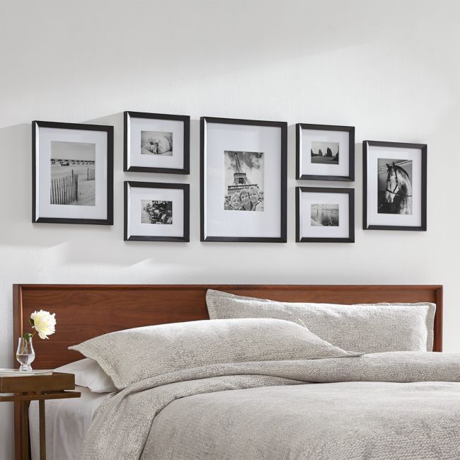 a bed with white sheets and pictures on the wall above it