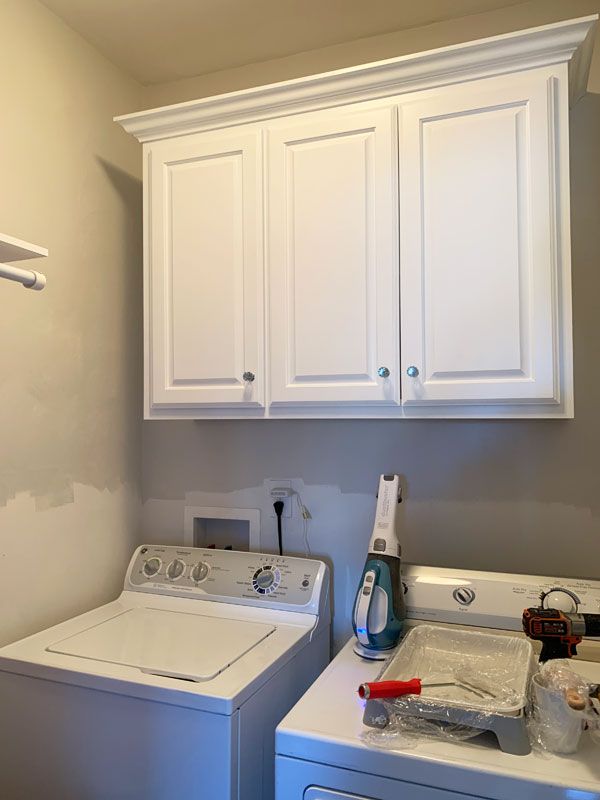 a white washer and dryer in a room with cabinets on the wall behind them