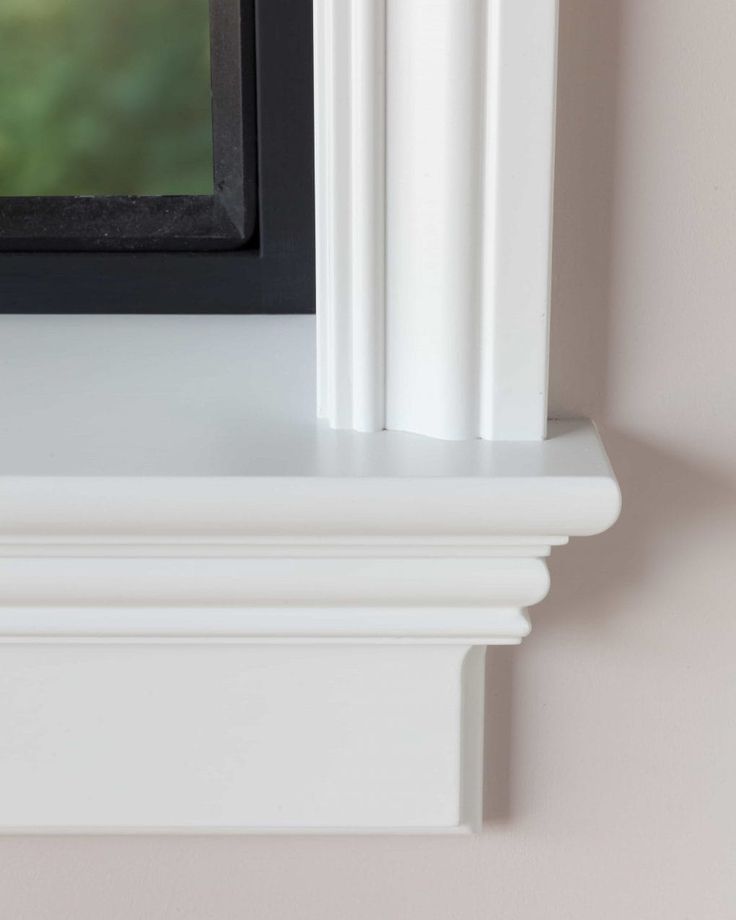 a black and white cat sitting on top of a shelf next to a framed photo