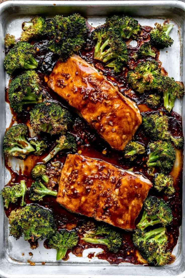 salmon and broccoli covered in sauce on a baking sheet