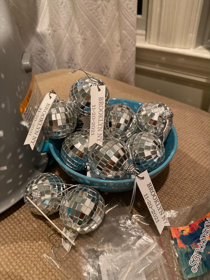 there are many disco balls in the bowl on the table with price tags attached to them