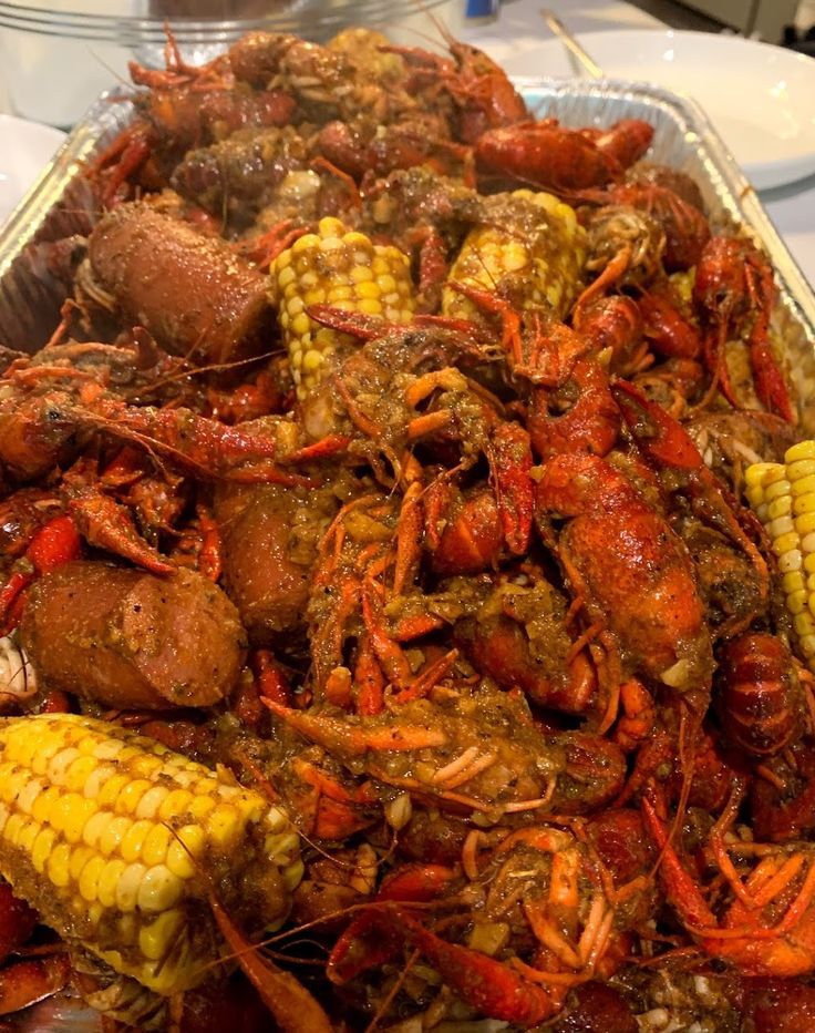 a tray filled with cooked crawfish and corn on the cob