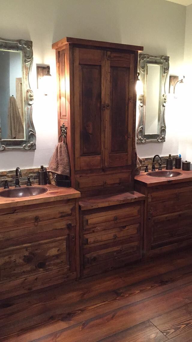 a bathroom with two sinks and wooden cabinets in the middle of it, along with mirrors on the wall