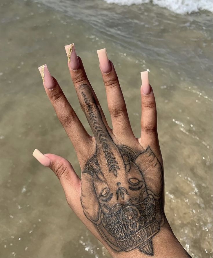 a person's hand with a tattoo on it and water in the back ground