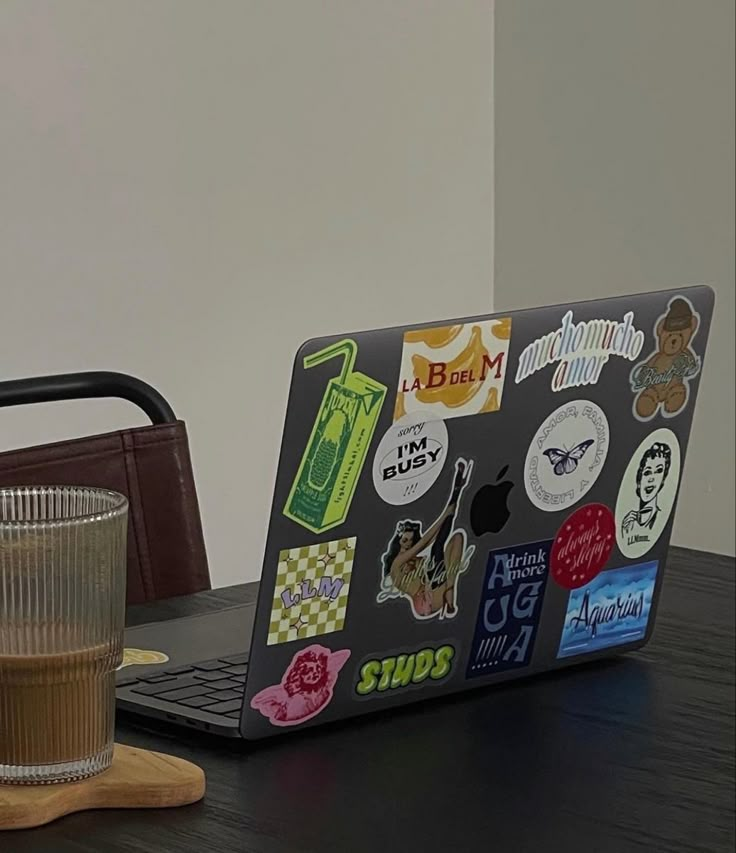 an open laptop computer sitting on top of a wooden desk next to a cup of coffee