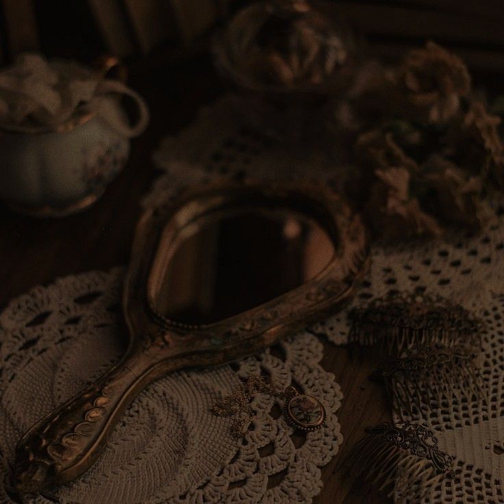 an antique mirror and doily on a table