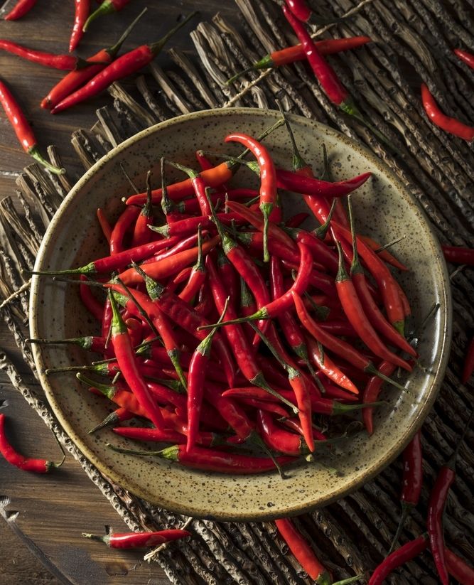 a bowl filled with red peppers on top of a wooden table