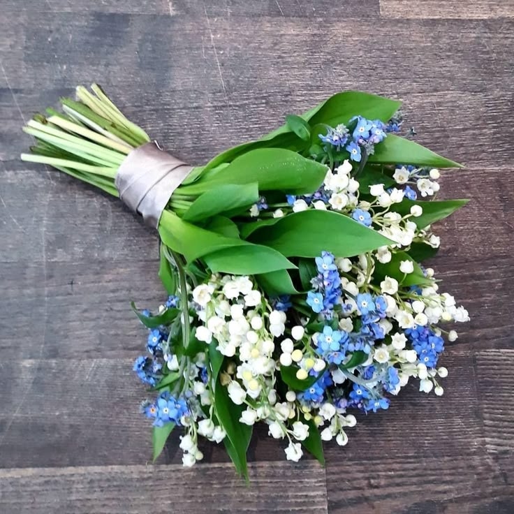 a bouquet of blue and white flowers sitting on top of a wooden table