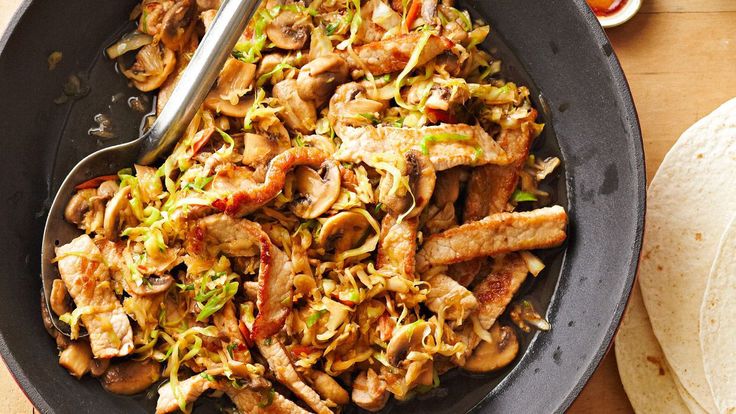 a skillet filled with meat and vegetables next to tortillas