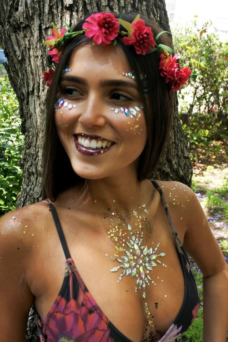 a woman with flowers painted on her face and chest standing in front of a tree