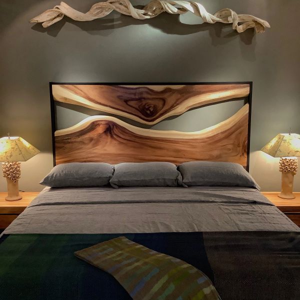 a bed with two lamps on either side and a wooden headboard above it in a bedroom