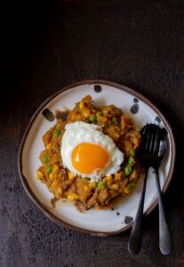 a white plate topped with rice and an egg on top of it next to a fork