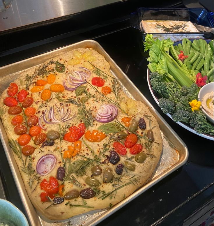 an uncooked pizza sitting on top of a pan next to other food items