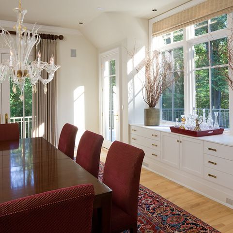 a dining room table with red chairs and chandelier in front of large windows