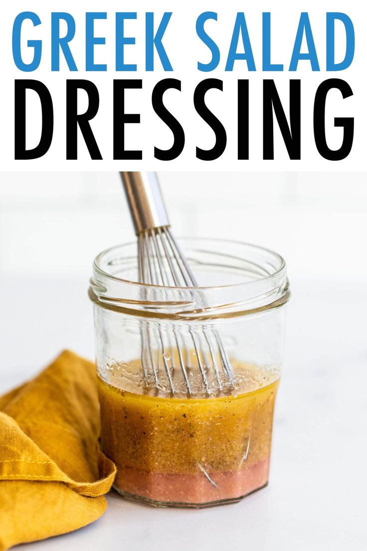 greek salad dressing in a glass jar with a whisk and yellow napkin next to it