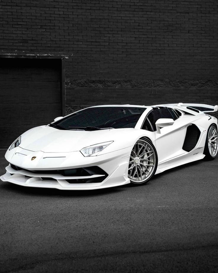 a white sports car parked in front of a brick wall