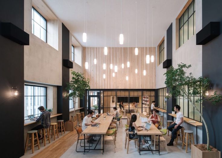 people are sitting at tables in the middle of a large room with high ceiling lights