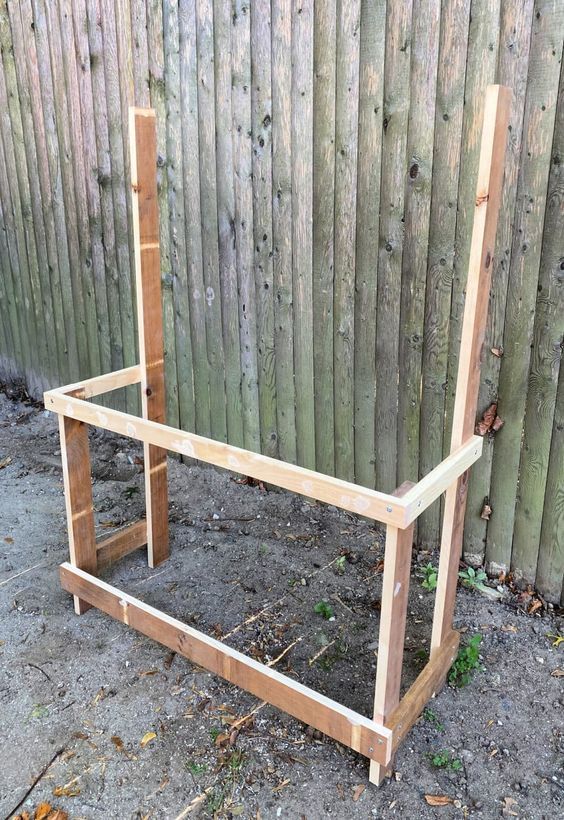 a wooden chair sitting on top of a dirt ground next to a fence with wood slats