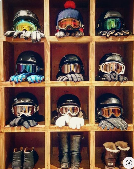 several pairs of ski goggles and gloves are on display in a cubby with wooden shelves