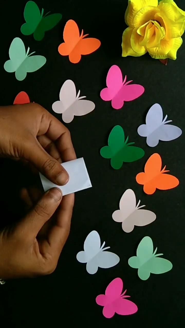 a person holding a piece of paper in front of some butterflies on a black surface