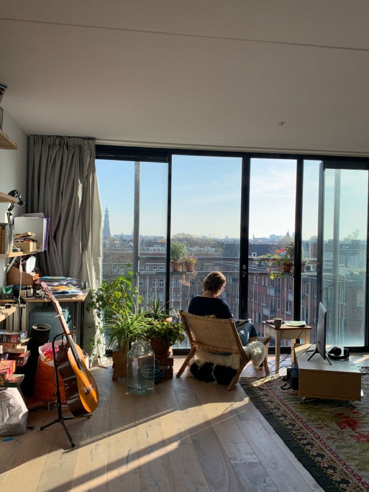 a person sitting on a chair in front of a window looking out at the city