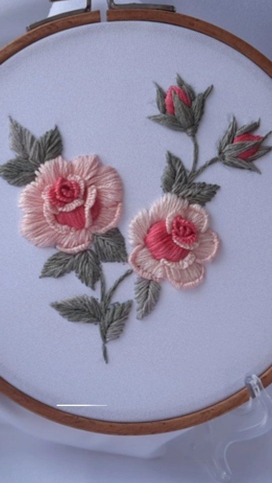 an embroidery project with pink flowers and green leaves