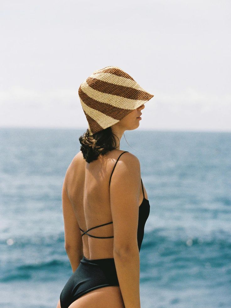 The Cyla Bucket Hat is handwoven in Madagascar using 100% Rafia Straw, utilising traditional, artisanal techniques. Designed to romanticise one's time spent in the sun, the Cyla Bucket Hat delicately balances practicality and luxury. Featuring our signature spiral weave, soft crochet construction and petite size, this piece was designed with travel in mind. Responsibly handwoven in Madagascar 100% Raffia Straw Brim: 6cm-8cm Available in 2 sizes. Size can be adjusted using the adjustable internal sweatband. The hat size can be reduced by up to 2cm. Care: Spot clean with a soft damp cloth and simply trim any small flyaway fibres that may pop up over time. Do not wash, do not bleach. Avoid getting wet. For more information about how to care for your hat visit our product care page.We recommen Brown Crochet Bucket Hat For The Beach, Brown Yarn Bucket Hat For The Beach, Summer Beige Bucket Hat In Toquilla Straw, Handmade Beige Straw Bucket Hat, Beige Adjustable Crochet Bucket Hat, Trending Hats, Frankies Bikinis, Women's Headwear, Dad Caps