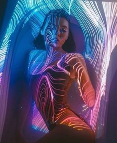 a woman is posing in front of an abstract light painting with her hands on her hips