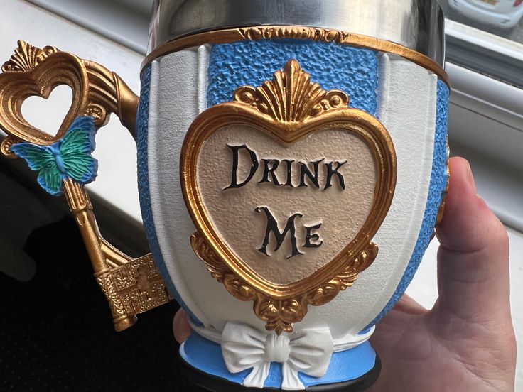 someone is holding up a wine glass with the words drink me on it and a key