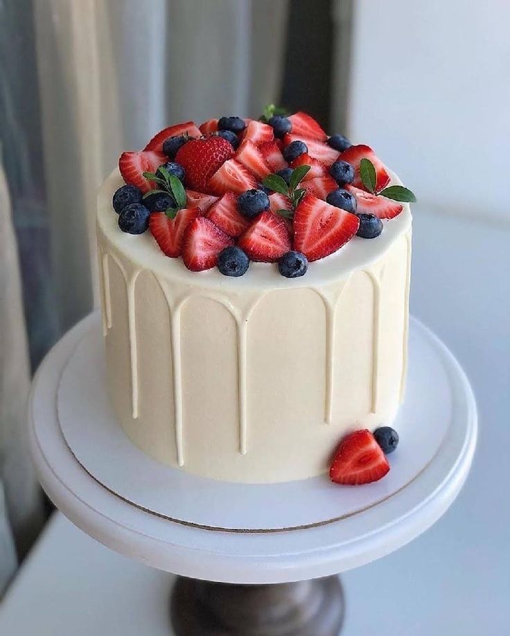 a white cake with strawberries and blueberries on top