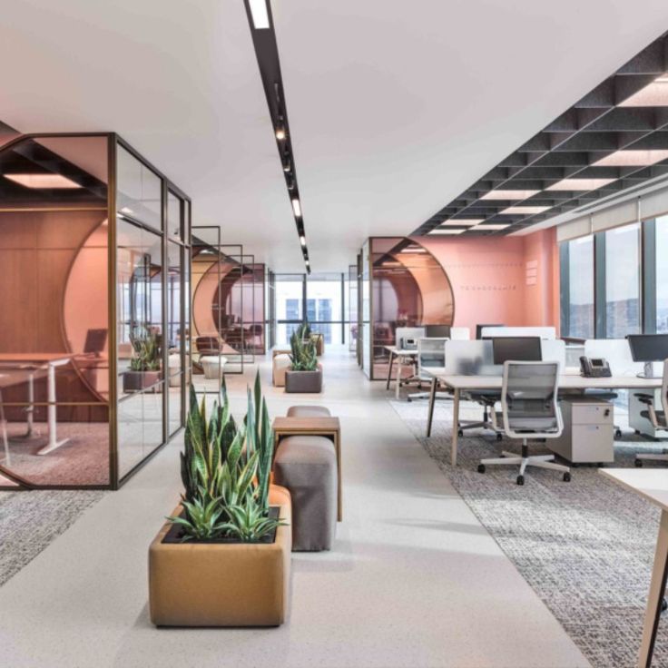 an office with pink walls and glass partitions on the ceiling, along with chairs and desks