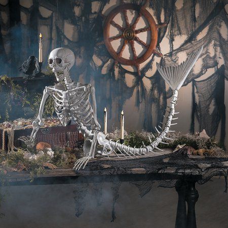 a skeleton sitting on top of a table with candles