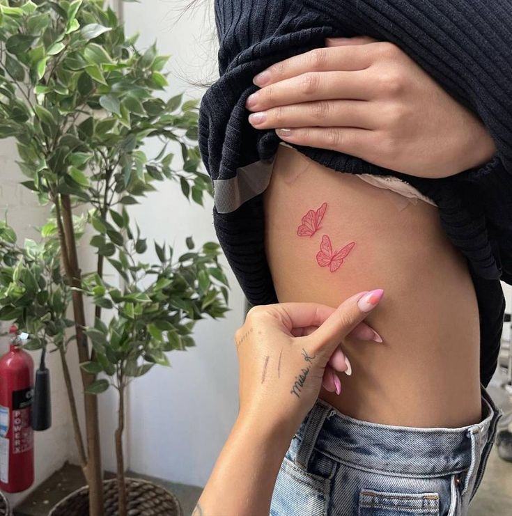 a woman is showing off her butterfly tattoo on her stomach and the other side of her body