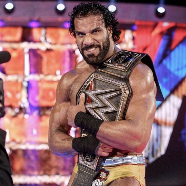 a man with a beard holding a wrestling belt