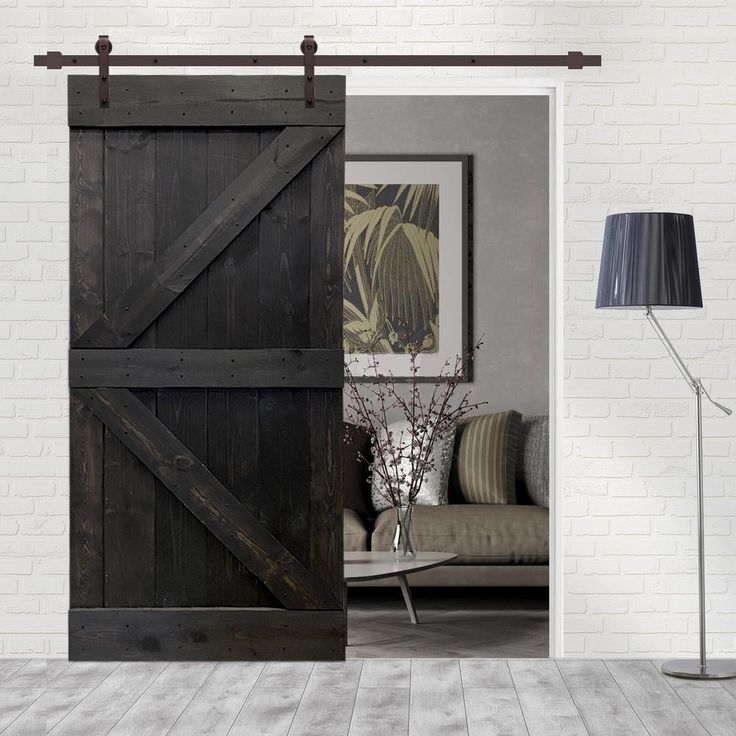 an open barn door in a living room with white brick walls and wood flooring