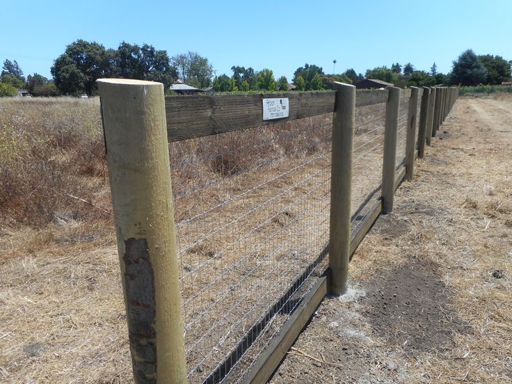 a wooden fence with a sign on it in the middle of a dry grass field