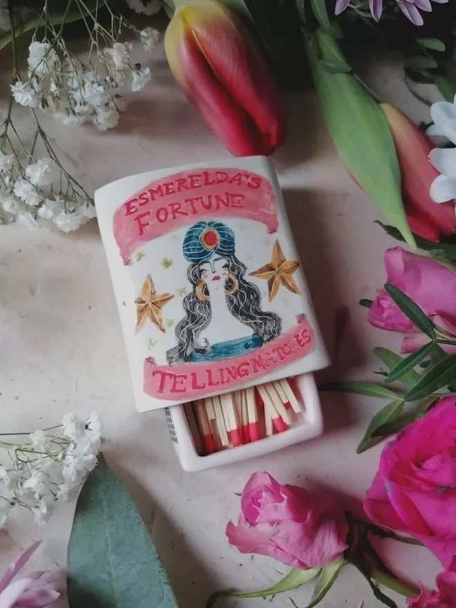 there is a matchbox with matches in it next to flowers