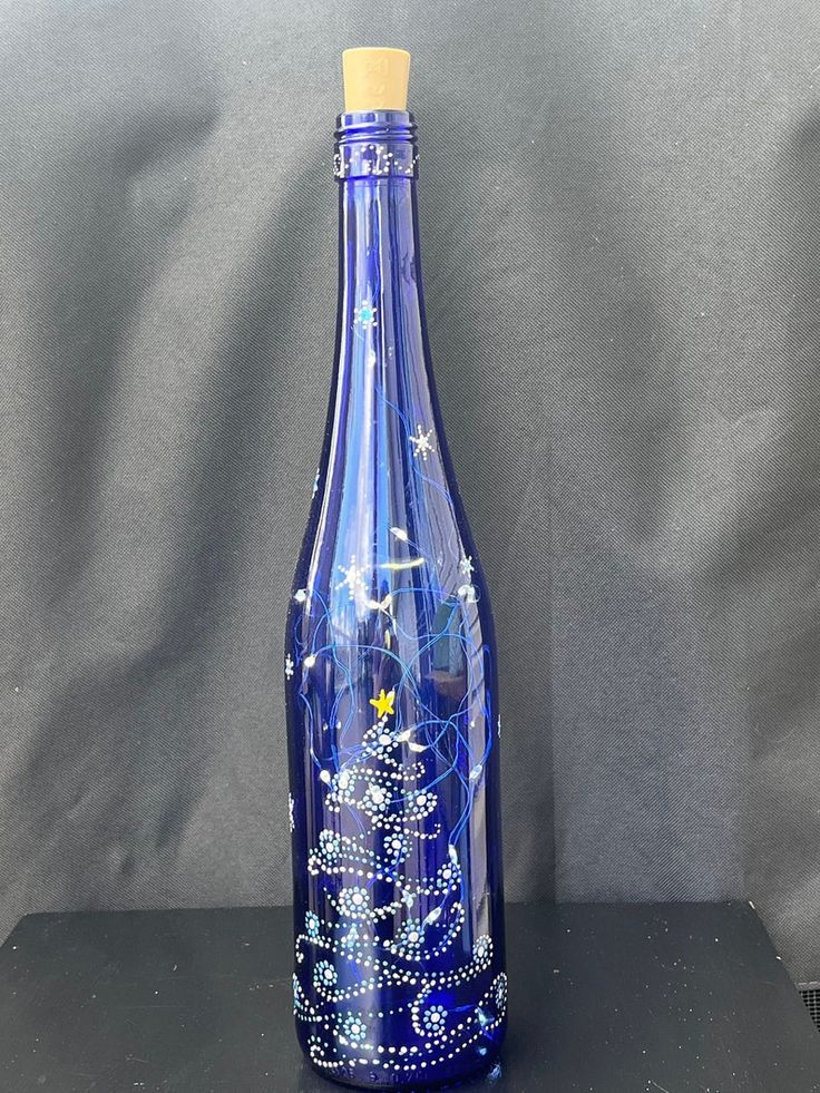 a blue glass bottle sitting on top of a black table next to a gray wall