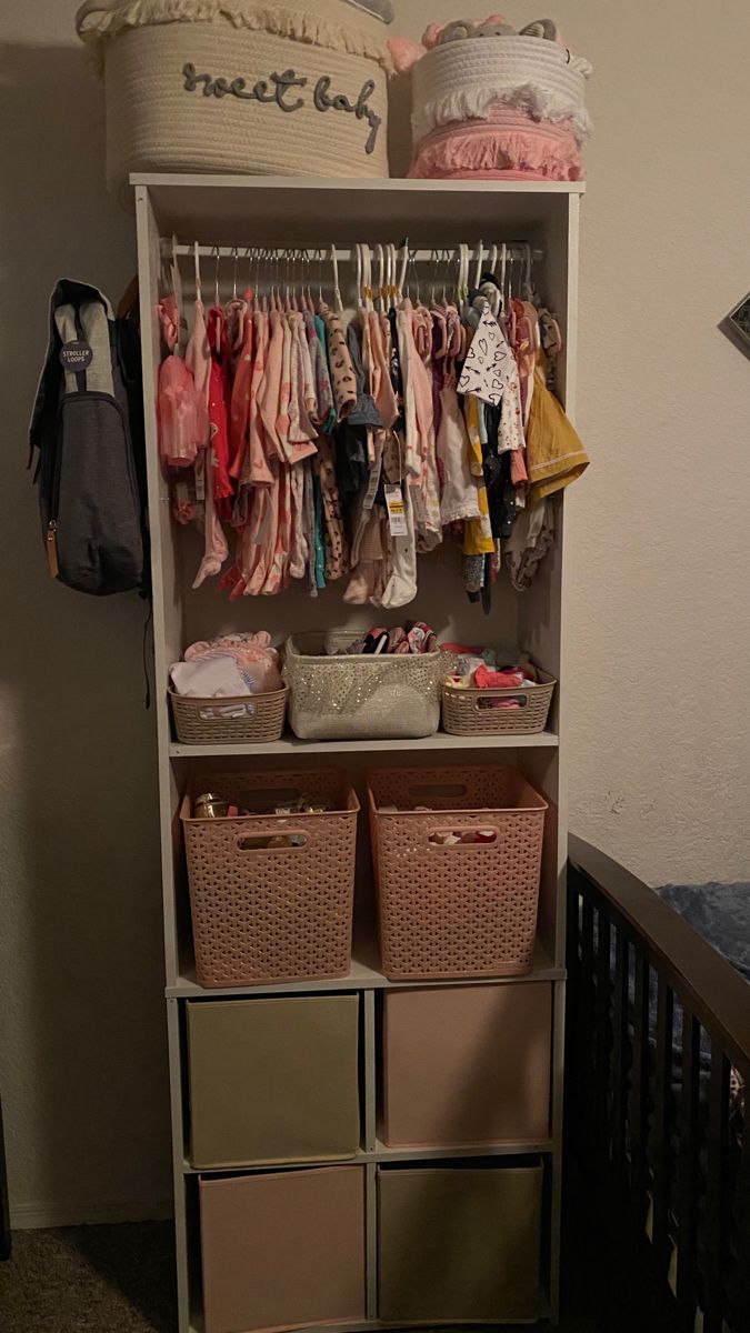 a baby's closet filled with lots of clothes and other items in baskets next to a crib