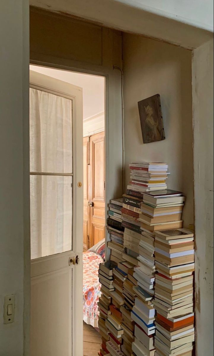 a stack of books sitting on top of a wooden floor next to an open door